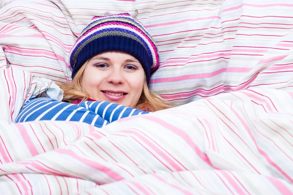 Улыбающаяся женщина в зимней шляпе, завернутая в одеяло — стоковое фото