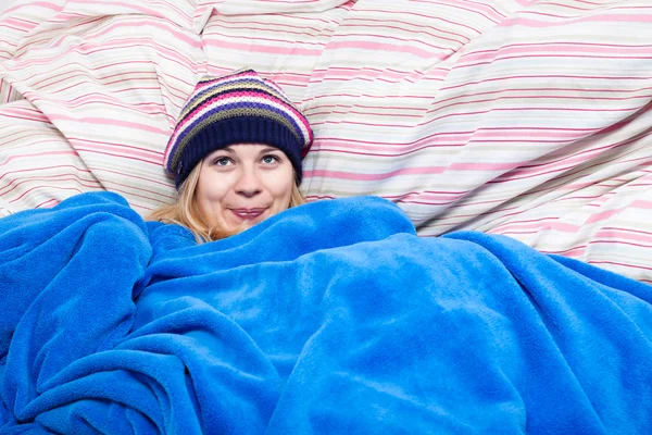 Leuke vrouw in winter hoed verpakt in dekbed — Stockfoto