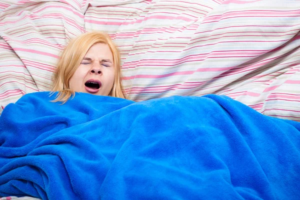 Сонная женщина зевает в одеяло — стоковое фото