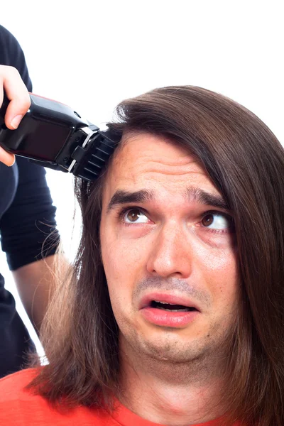 Unhappy man being shaved with hair trimmer Stock Photo