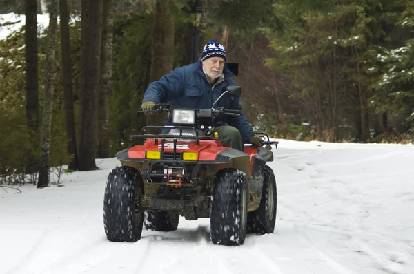 Senior riding ATV quad on the snow — Stock Photo, Image