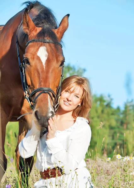 花のフィールドで彼女の馬を持つきれいな女性 — ストック写真