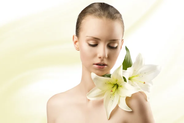 Beauty portrait with flowers, she looks lilies — Stock Photo, Image