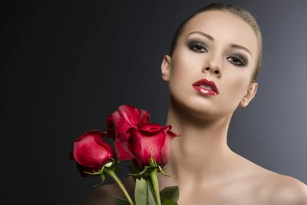 Flickans låg nyckel porträtt med rosor, hon ser i linsen — Stockfoto