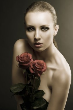 Gilr's low key portrait with roses near her breast clipart