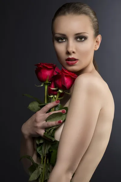 Gilr's låg nyckel porträtt med rosor nära hennes ansikte — Stockfoto