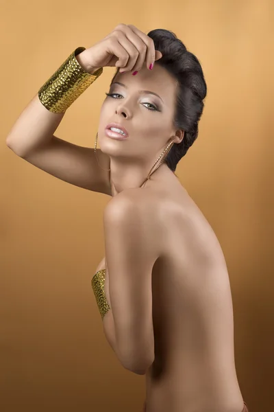 Bruna sexy con due braccialetti d'oro, con mano vicino alla fron — Foto Stock
