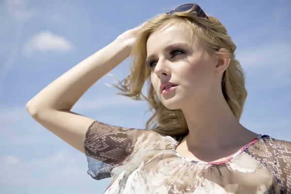 Belle fille en lunettes de soleil sur fond bleu ciel — Photo