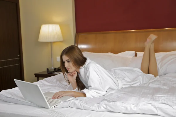 Porträt einer schönen Frau mit Laptop auf dem Bett — Stockfoto