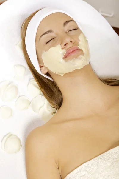 Mujer joven recibiendo tratamiento de máscara de piel de belleza en su cara con —  Fotos de Stock