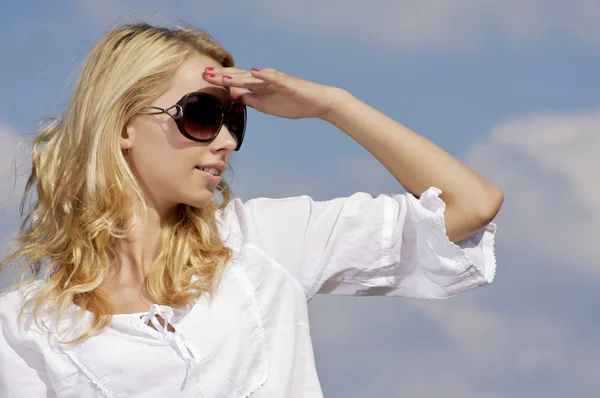 Vacker flicka i solglasögon på bakgrunden blå himmel Royaltyfria Stockbilder
