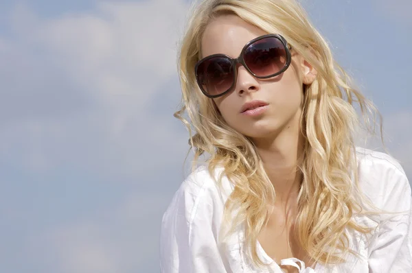 Krásná dívka v sluneční brýle na pozadí modré oblohy — Stock fotografie