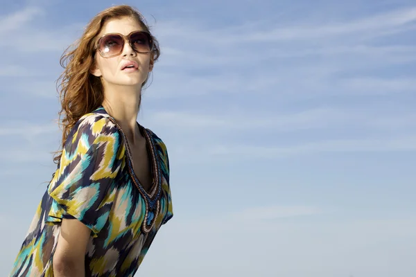 Menina bonita em óculos de sol no fundo céu azul — Fotografia de Stock