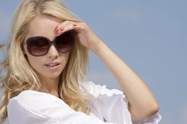 Beautiful girl in sunglasses on background blue sky Stock Photo