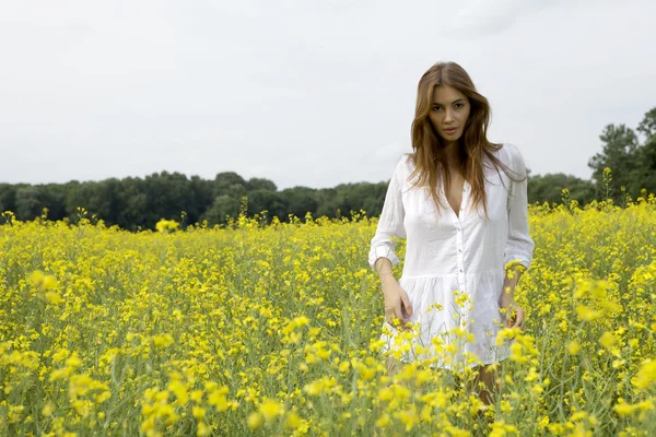 Brunette vrouw in een gele bloemen veld — Stockfoto