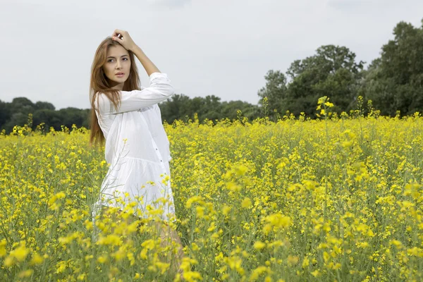 Брюнетка жінка в полі жовті квіти — стокове фото