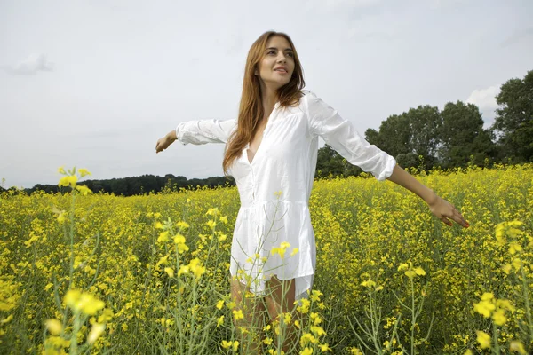 Brünette Frau in einem gelben Blumenfeld — Stockfoto