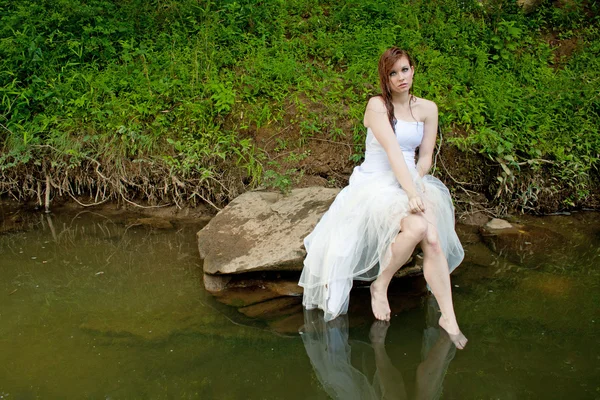 Mokre kobieta siedzi na skale nad wodą — Zdjęcie stockowe