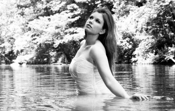 A black and white photo of a bride in water