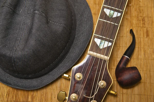 Tubería, sombrero y guitarra en el fondo de madera Imagen De Stock
