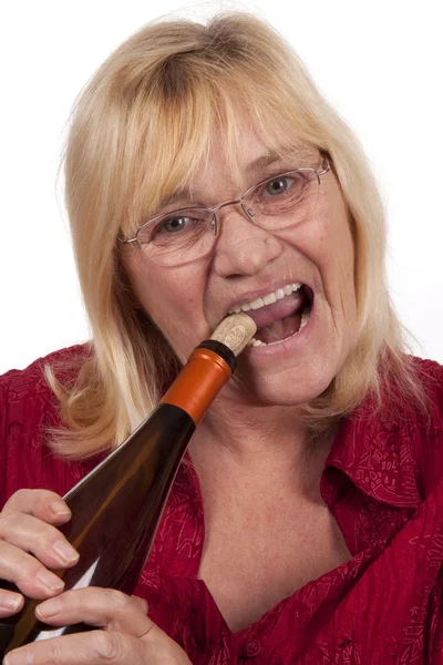 stock image Elderly blond woman opening a bottle
