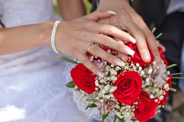 Händer med vigselringar och en bröllop bukett — Stockfoto