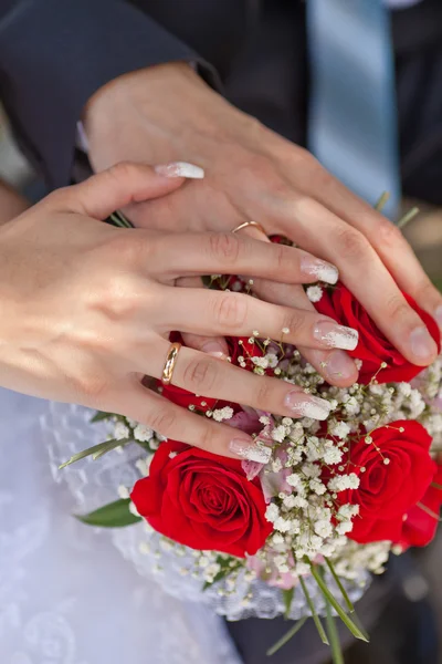 Händer med vigselringar och en bröllop bukett — Stockfoto