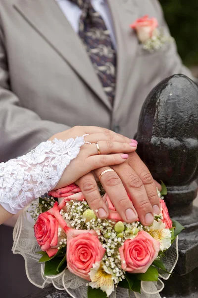 Bröllopsbukett och händer med vigselringar — Stockfoto