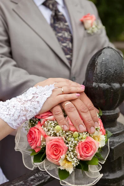 Bruiloft boeket en handen met trouwringen — Stockfoto
