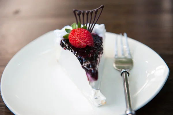 Piece of Blueberry Cheesecake topping with fresh strawberries on white plate closeup — Stock Photo, Image