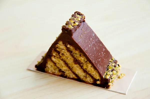 Pedazo de pastel sobre fondo de patrón de madera: Triángulo de pistacho de chocolate —  Fotos de Stock