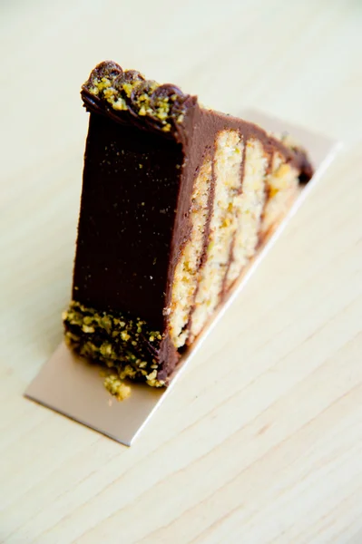 Pedazo de pastel sobre fondo de patrón de madera: Triángulo de pistacho de chocolate —  Fotos de Stock