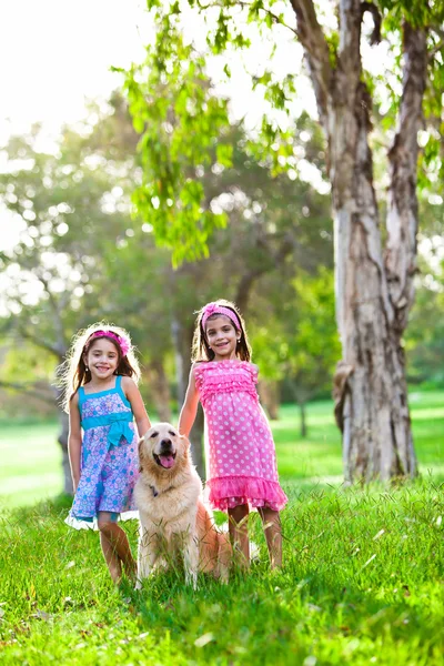 Duas meninas felizes e um golden retriever — Fotografia de Stock