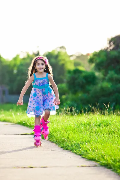 Menina feliz montando em lâminas de rolo no parque — Fotografia de Stock