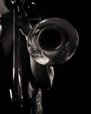 Man playing a trombone, strong contrasting side-light, monochrome version clipart