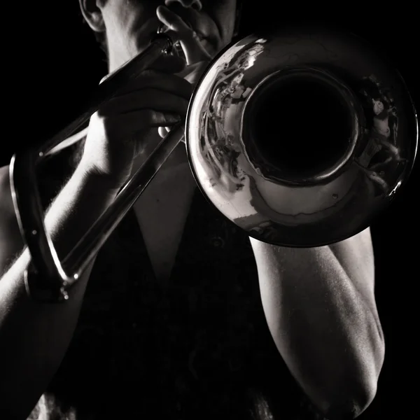 Человек играет на тромбоне; сильный контрастный боковой свет; монохромная версия ; — стоковое фото