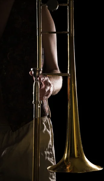 Homme tenant un trombone ; forte lumière latérale contrastée ; version couleur — Photo
