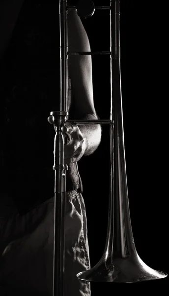 Homme tenant un trombone ; forte lumière latérale contrastée ; version monochrome — Photo