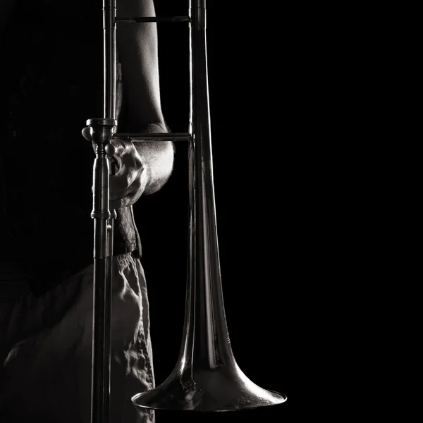 Hombre sosteniendo un trombón; fuerte contrastante de luz lateral; versión monocromática —  Fotos de Stock
