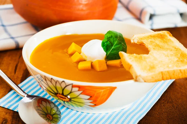 stock image Pumpkin soup with cream in a bowl with painted flower and toast