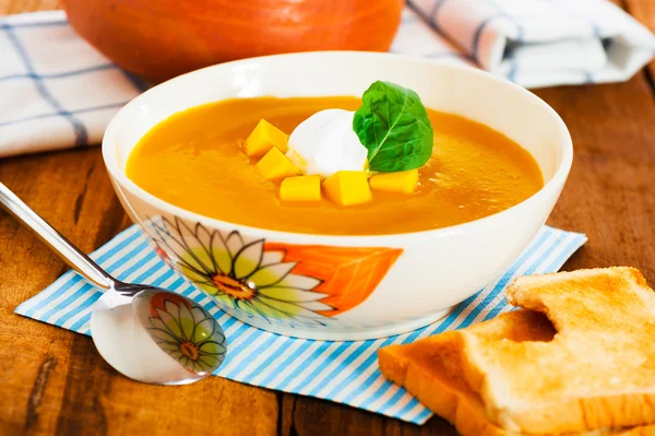 stock image Pumpkin soup with cream in a bowl with painted flower and toast