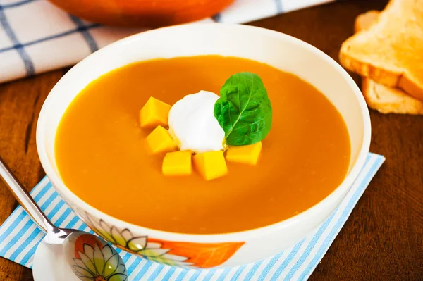 stock image Pumpkin soup with cream in a bowl with painted flower and toast