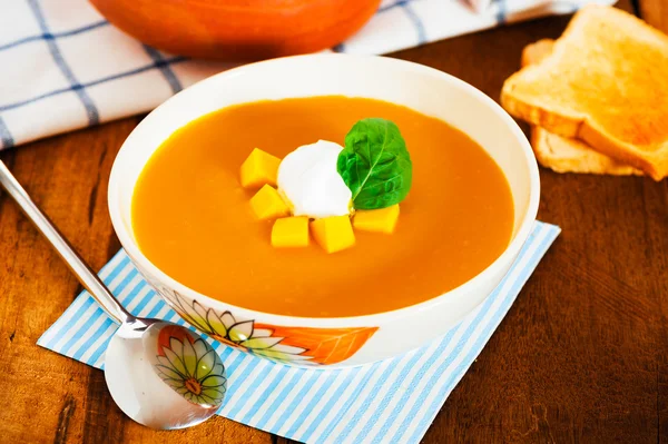 stock image Pumpkin soup with cream in a bowl with painted flower and toast