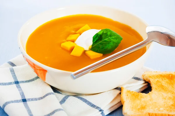 stock image Pumpkin soup with cream in a bowl with painted flower and toast