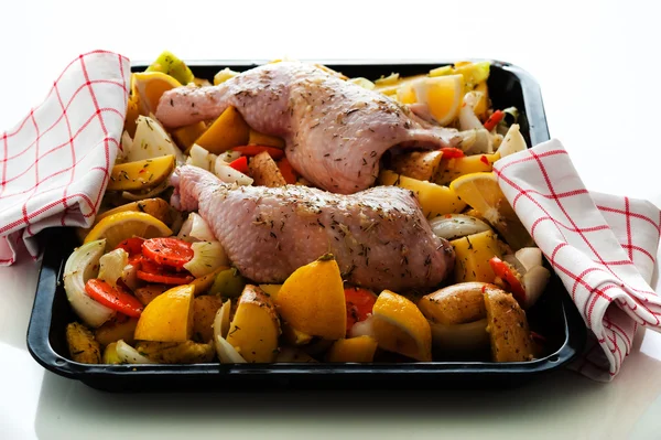 Ruwe gemarineerde kip dijen met groenten op een bakplaat — Stockfoto