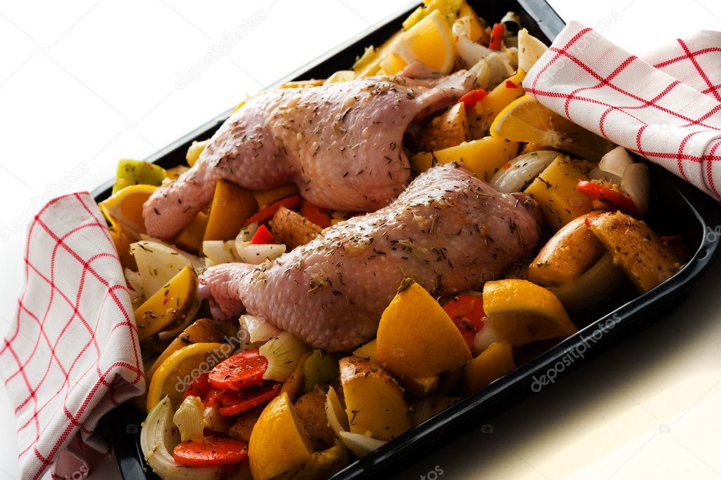Raw marinated chicken thighs with vegetables on a baking tray