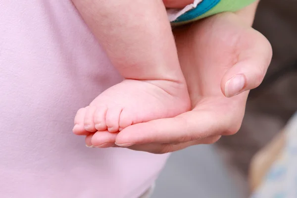 Liten baby foten på en hand — Stockfoto