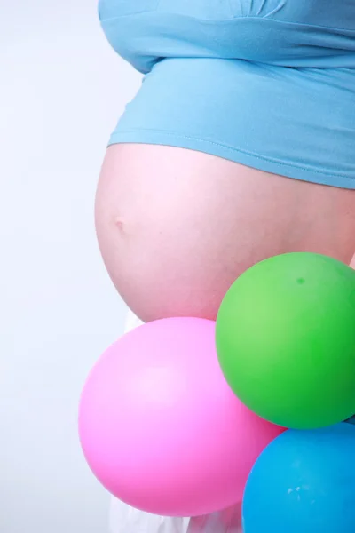 Студийное изображение беременной женщины с воздушными шарами на белом фоне — стоковое фото