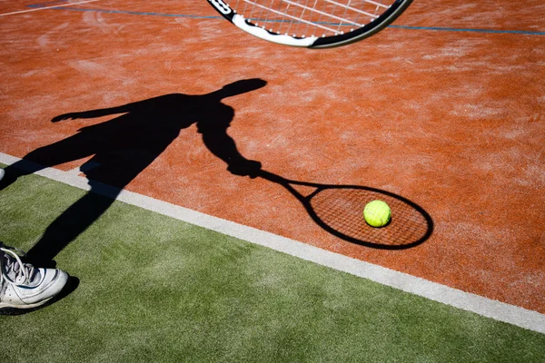 Schaduw van een tennisspeler in actie op een tennisbaan — Stockfoto