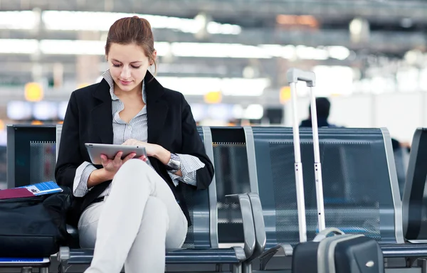 Młodych kobiet pasażerów na lotnisku, za pomocą swojego komputera typu tablet — Zdjęcie stockowe